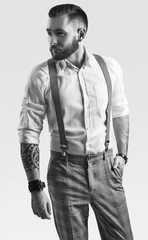 Brutal elegant man in gray classic pants and suspenders isolated on white