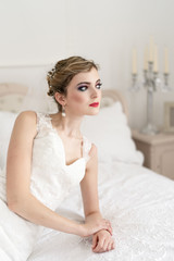 Fototapeta na wymiar Young woman in wedding dress lying on white bed