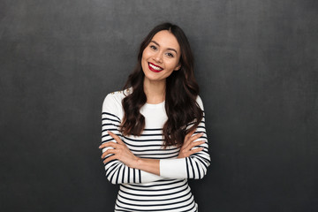 Happy brunette woman in sweater posing with crossed arms