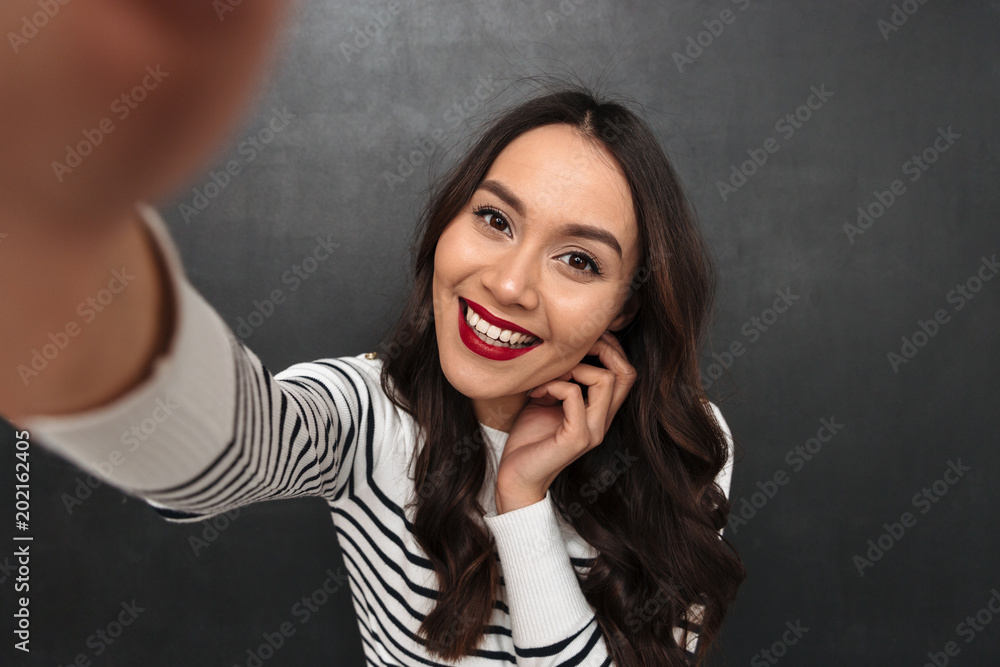 Poster Smiling brunette woman in sweater making selfie