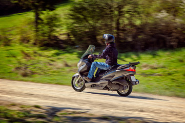 Fototapeta na wymiar Person riding a scooter on a dirty road in countryside