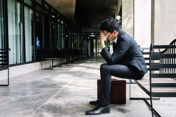 Concept of business failure and unemployment problem.An unemployed businessman sits alone in the corridor of an office. Is stressed about the future. - obrazy, fototapety, plakaty