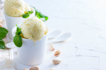 Homemade pistachio ice cream in white ceramic cups on a white table, copy space