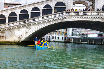 Fototapeta na wymiar VENICE, ITALY - circa MAR, 2016: Rowing boat team under Rialto Bridge in Venice, Italy