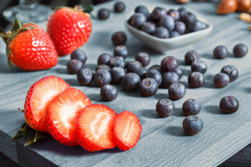 Obraz na płótnie Canvas Sliced strawberry with blueberries on a wooden table