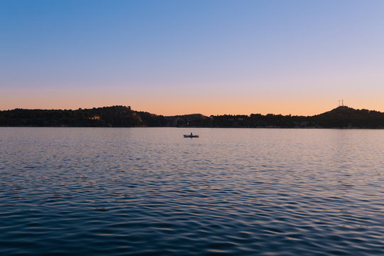 Minimalistisch - Sonnenuntergang &uuml;ber dem Meer mit Bergsilhouette mit Boot Sportler