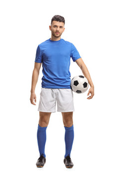 Soccer player holding a football and looking at the camera