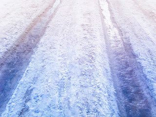 Streams of melted snow on a snowy road tracks in the spring day.