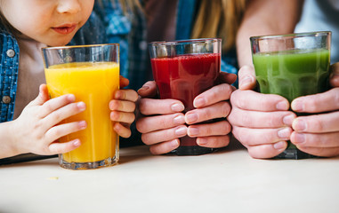 Family holding a glass of juice in hands.