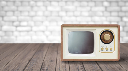 Old tv tunner on a wooden table against a white brick wall. Empty copy space for Editor's text.