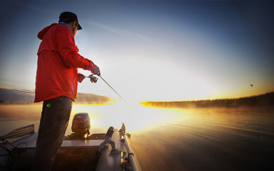 Man fishing on a sunset lake.