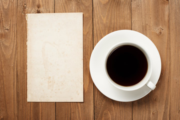cup of coffee on wooden boards, blank paper sheet with place for text - holiday and greeting concept