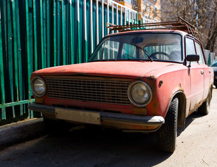Parked old rusty red Soviet car.
