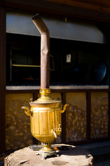 A gold samovar with a pipe stands on a stump.