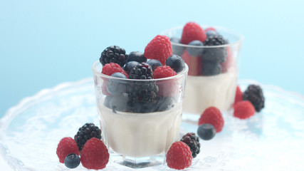 glasses with greek yogurt with berries Minimalism food on blue background. Panna cotta with strawberry raspberry, blueberry