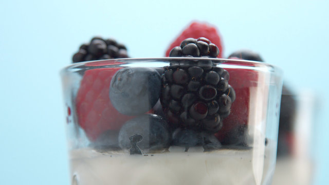 glasses with greek yogurt with berries Minimalism food on blue background. Panna cotta with strawberry raspberry, blueberry