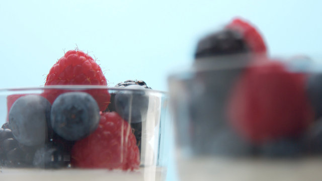 glasses with greek yogurt with berries Minimalism food on blue background. Panna cotta with strawberry raspberry, blueberry