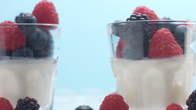glasses with greek yogurt with berries Minimalism food on blue background. Panna cotta with strawberry raspberry, blueberry