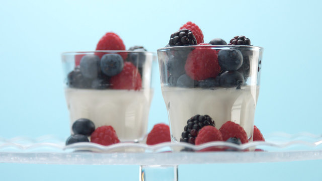 glasses with greek yogurt with berries Minimalism food on blue background. Panna cotta with strawberry raspberry, blueberry