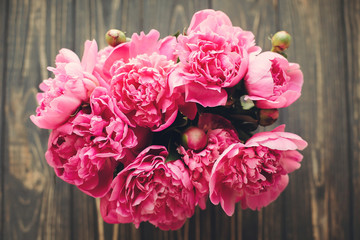 pink peonies bouquet on rustic dark wooden background, top view, space for text. floral greeting card mock-up, flat lay. happy mothers day concept. pink flowers, floral image