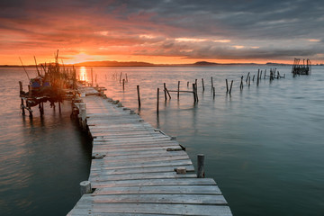 Sunset landscape of artisanal fishing boats in the old wooden pier. Carrasqueira is a tourist destination for visitors to the coast of Alentejo near Lisbon.