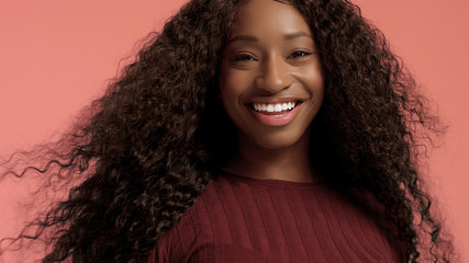 Beauty mixed race african american woman with hair blowed in air smiling at camera