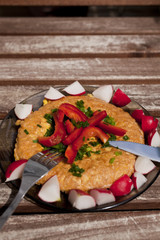 Omelette with vegetables on a wooden table outside
