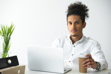 handsome young african american businessman using laptop and looking at camera
