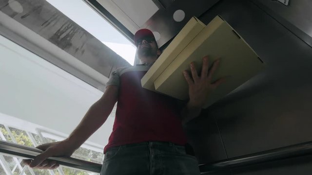 Smiling pizza delivery man delivering pizzas in the stylish house.