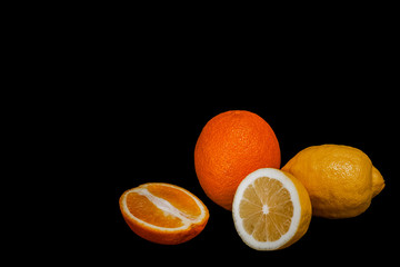 Fresh lemon with half and an orange with half isolated on black background.