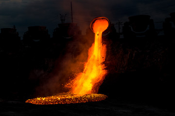 Blast furnace slag discharge at metallurgical plant, colorful hot lava flow, industrial landscape of iron foundry