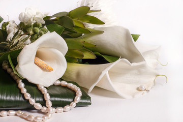 bouquet with white Calla lilies and a string of freshwater pearls on a white background