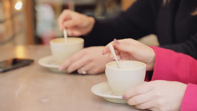 Closeup of friends mixing sugar and drink coffee cup