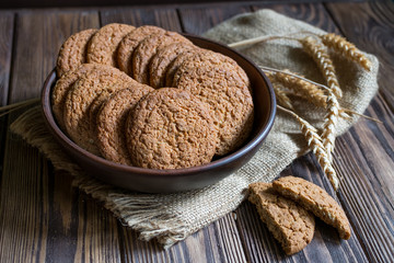 Oat cookies in a plate on dark wooden background. Healthy food, breakfast, snack. Raw meal.