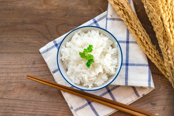 cooked rice in bowl with chopsticks on the wooden background.