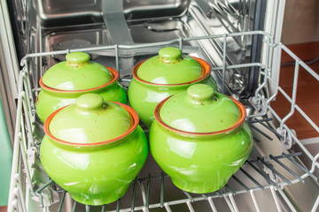 Four green ceramic pots lie in the lower compartment of the dishwasher