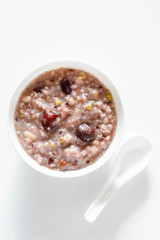 Eight Treasure Congee on traditional chinese festive porridge, mixed from eight ingredients: red beans, lotus seeds, peanuts, dates, pine nuts, lily, almond and walnut on white wooden table, top view