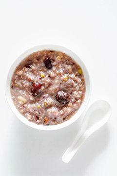 Eight Treasure Congee on traditional chinese festive porridge, mixed from eight ingredients: red beans, lotus seeds, peanuts, dates, pine nuts, lily, almond and walnut on white wooden table, top view