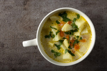 Healthy soup in white bowl with carrot, potatoes and parsley