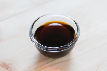 Soy sauce in a glass bowl on wooden background