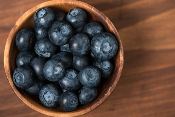 Fresh blueberry in wooden bowl on wooden table.