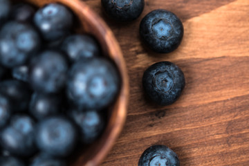 Fresh blueberry in wooden bowl on wooden table.