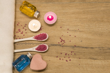 spa concept. pink bath salt , bath gel with candle on the wooden background