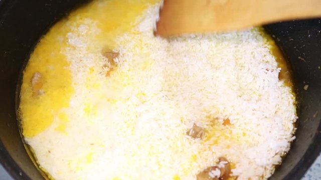Preparation of rice dishes - pilaf from Uzbekistan. The rice is evenly distributed over the entire area of the pan.