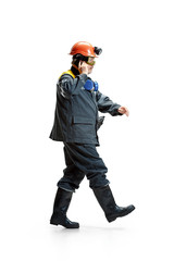 The studio shot of serious senior bearded male miner in motion at the camera with smartphone on a white background.
