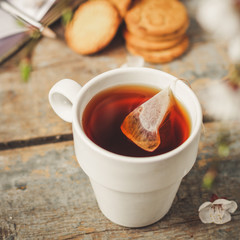 tea brew in a cup (tea bag) on ​​a wooden table and flowering spring twigs. Food background - drink background