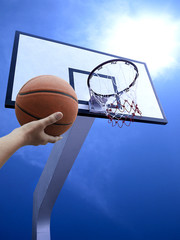 a man play basketball. Low angle view of basketball hoop against blue sky