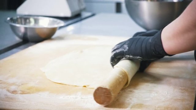 Woman baker prepares dough for apple pie in commercial kitchen