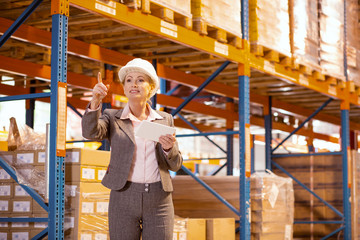 Obraz na płótnie Canvas Professional businesswoman. Strict professional businesswoman holding a tablet while controlling the working process in the warehouse