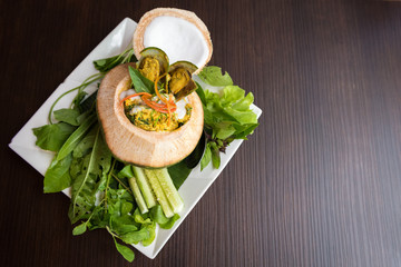 Steamed curry seafood in coconut on wooden table, Thai food